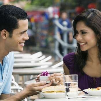 Mid adult man proposing to a young woman at a sidewalk cafe