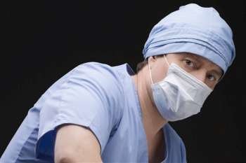 Close-up of a male surgeon wearing scrubs and a surgical mask