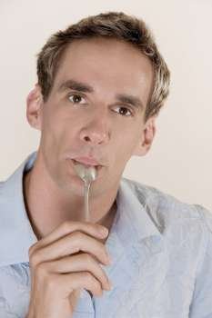 Portrait of a mid adult man licking a teaspoon
