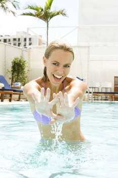 Portrait of a young woman gesturing with her hands in a swimming pool