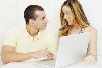 Close-up of a young couple looking at each other in front of a laptop