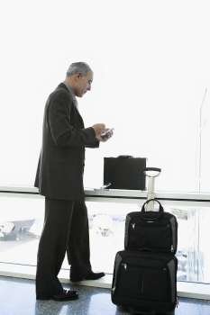 Side profile of a businessman using a palmtop in the waiting room of an airport