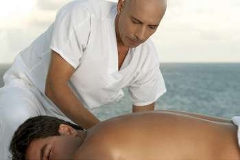 Close-up of a massage therapist massaging a mid adult man´s back