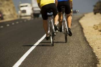 Low section view of two people cycling on the road