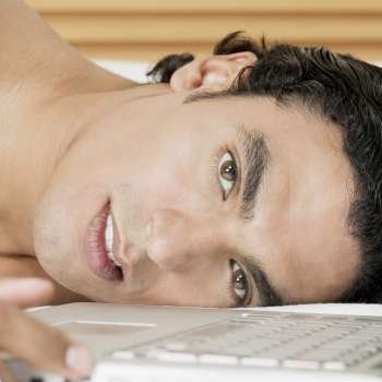 Portrait of a young man lying near a laptop