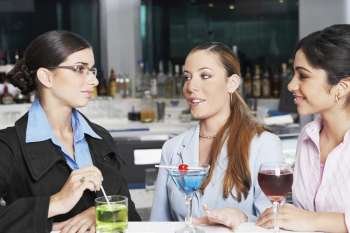 Close-up of three businesswomen talking in a bar