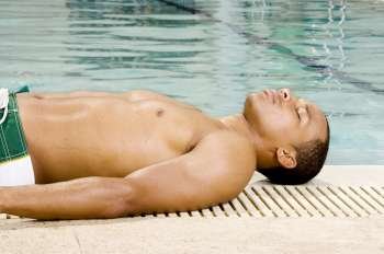 Side profile of a young man lying at the poolside