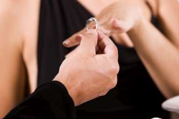 Close-up of a man putting an engagement ring on a young woman´s finger