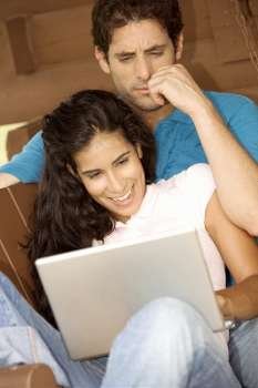 Close-up of a mid adult man and a young woman looking at a laptop