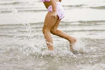 Low section view of a girl running in water on the beach