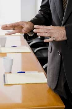 Mid section view of a businessman gesturing in a conference room
