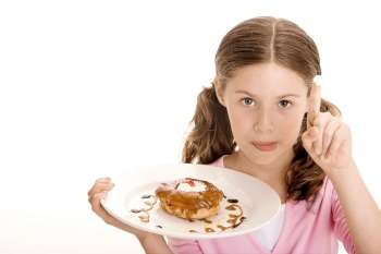 Portrait of a girl holding a donut in a plate with cream on the tip of her finger