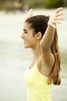 Side profile of a girl standing on the beach with her arms outstretched