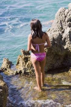 Rear view of a girl standing near a rock in the sea, Capri, Campania, Italy