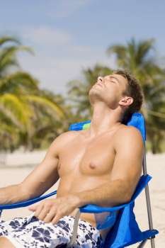 Young man relaxing on a lounge chair at the beach