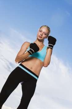 Low angle view of a young woman wearing boxing gloves