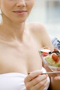 Close-up of a young woman holding a bowl of fruit salad