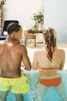 Rear view of a young couple standing in a swimming pool