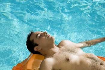 High angle view of a young man lying on a raft in a swimming pool