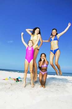 Two young women and two girls jumping on the beach