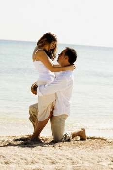 Side profile of a young woman and a mid adult man embracing each other on the beach