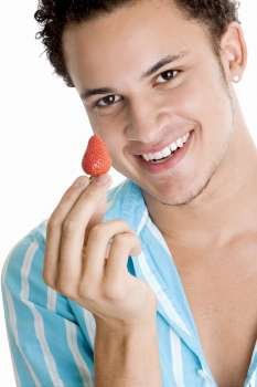 Portrait of a young man holding a strawberry