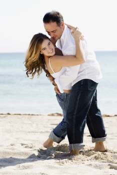 Mid adult man embracing a young woman on the beach