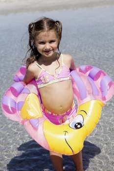 Girl in an inflatable ring standing on the beach