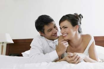 Close-up of a newlywed couple lying on the bed and smiling