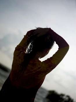Silhouette of a young woman with her hands on her head