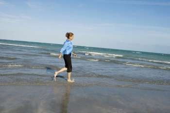Side profile of a mid adult woman walking on the beach