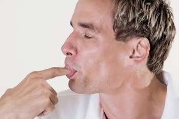 Close-up of a mid adult man licking his finger