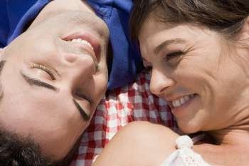 High angle view of a mid adult couple lying on a picnic blanket and smiling