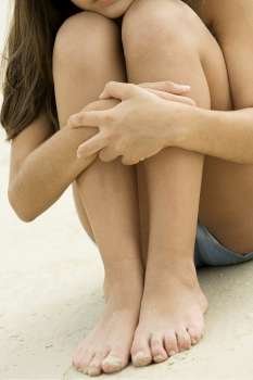 Close-up of a girl sitting hugging her knees