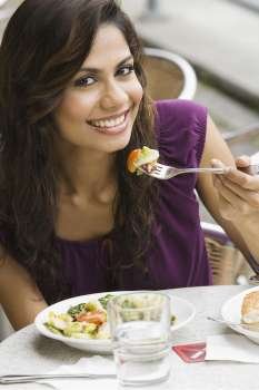 Portrait of a young woman eating salad at a sidewalk cafe