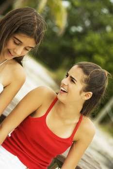 Close-up of girl and a teenage girl sitting together smiling on the beach