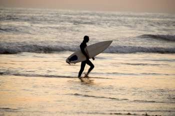 Side profile of a surfer walking on the beach, San Diego Bay, California, USA