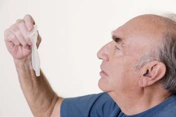 Side profile of a senior man holding a condom
