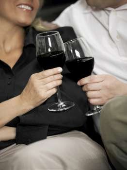 Close-up of a woman and a man toasting with wine glasses