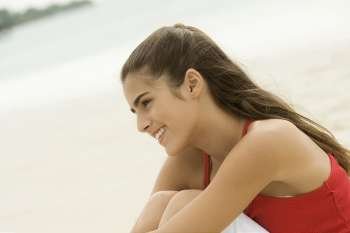 Side profile of a girl sitting on the beach smiling