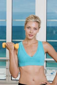 Portrait of a young woman holding a dumbbell