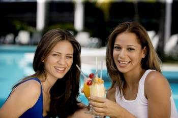 Portrait of two young women holding juice glasses