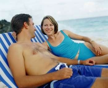Close-up of a young couple lying on lounge chairs and smiling, Bermuda