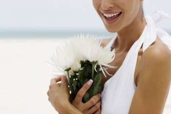 Close-up of a young woman holding flowers on the beach