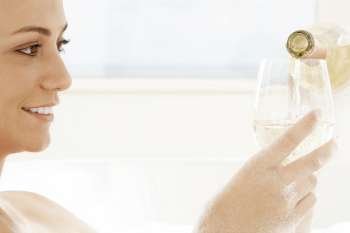 Close-up of a young woman pouring white wine into a wineglass
