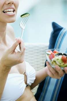 Close-up of a young woman eating salad with a fork