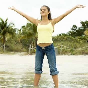 Girl standing on the beach with her arms outstretched