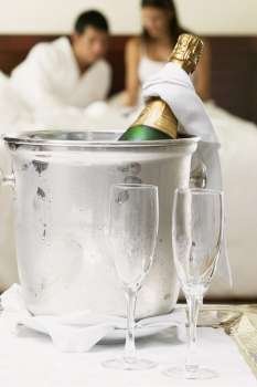 Close-up of a champagne bottle in an ice bucket with two champagne flutes
