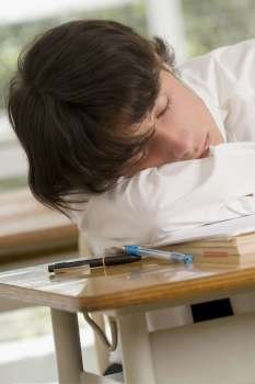 Close-up of a young man sleeping on desk in a classroom