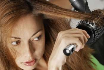 Close-up of a young woman drying her hair with a hair dryer